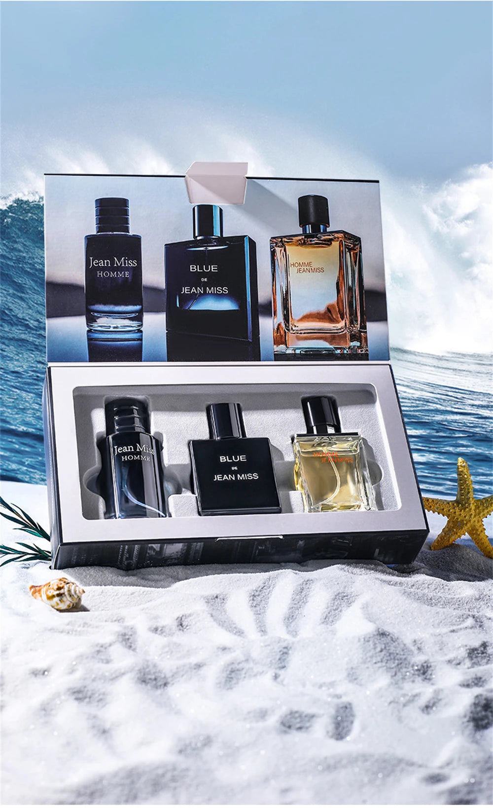 Three glass cologne bottles for men in a gift box, featuring dark blue and amber liquids, on a beach setting.