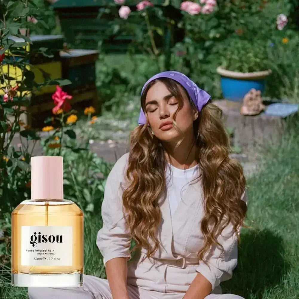 Gisou honey-infused essence oil in a clear glass bottle with a pink cap, set against a woman in a garden background.