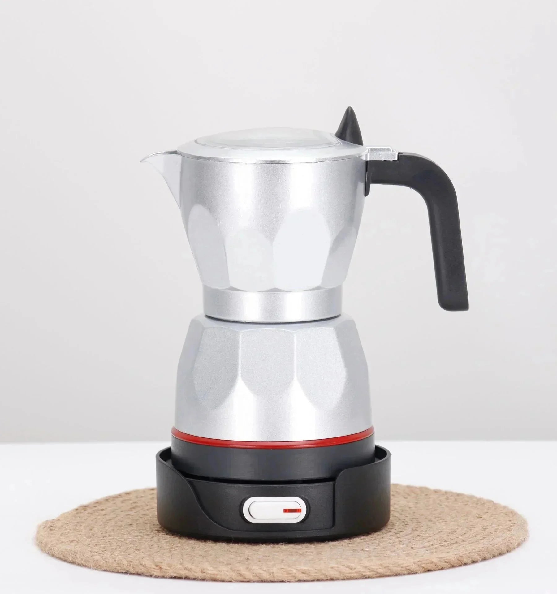 Silver aluminum electric moka pot coffee maker with black handle and base on a jute mat.