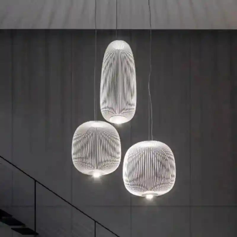 Three white, cage-style pendant lights with vertical slats, hanging at varying heights for modern interior illumination.
