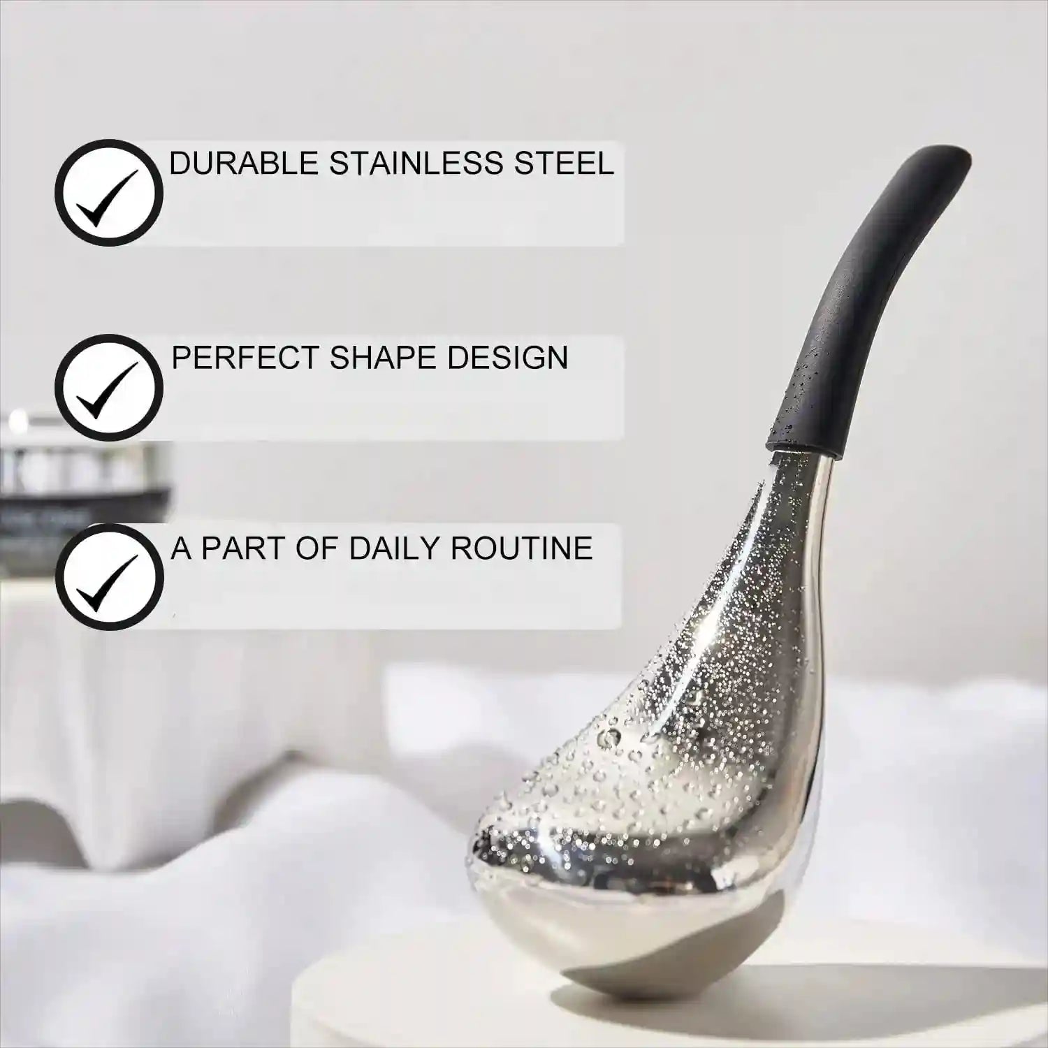 Stainless steel facial massage tool with a black handle, featuring a teardrop shape covered in water droplets.