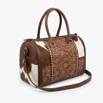 Genuine leather mini duffel trunk with floral tooling and brown-white cowhide panels, zipper closure, and shoulder strap.