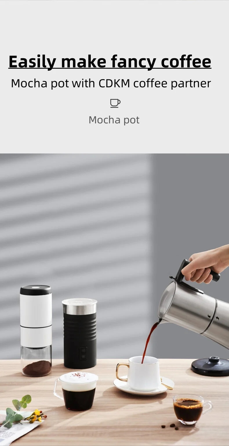 CDKM mocha pot stainless steel coffee maker pouring coffee into a white cup next to a milk frother and grinder.