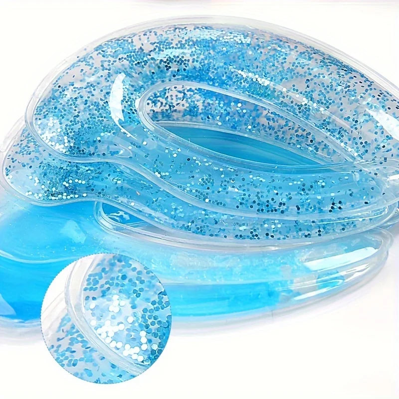 Two blue, crescent-shaped gel eye patches with blue glitter, set against a white background.